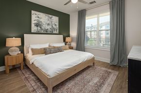 Morrisville apartment for rent - A bedroom with a large bed and a painting on the wall.