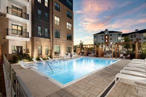 Morrisville apartment for rent - A swimming pool surrounded by lounge chairs in front of apartment buildings.