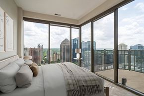 Atlanta apartment for rent - A bedroom with a large bed and a view of the city.