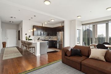 Atlanta apartment for rent - A modern living room with a brown couch and a kitchen in the background.
