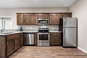Belton apartment for rent - Senior Apartments Near Belton, MO for Rent - Traditions Villas 55+ - Kitchen with a High Ceiling, Vinyl Plank Flooring, Custom Cabinetry, Granite Countertops, and Stainless Steel Appliances.