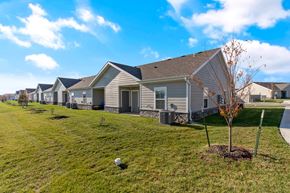 Belton apartment for rent - Two-Bedroom Senior Townhomes in Belton, MO - Traditions Villas 55+ - A Lawn Fronting a Row of Houses, and a Tree.