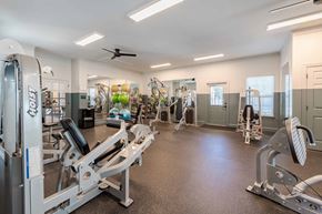 Knightdale apartment for rent - A spacious gym with a variety of equipment including treadmills, weight machines, and a ceiling fan.