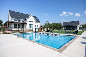 San Antonio apartment for rent - a swimming pool with chaise lounge chairs and a house in the background