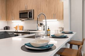 Austin apartment for rent - A modern kitchen with a white countertop and a microwave above it.