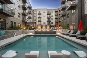 Austin apartment for rent - A swimming pool surrounded by lounge chairs and umbrellas in a residential area.