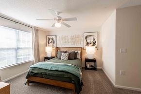 Winston Salem apartment for rent - A bedroom with a bed, two lamps, and a ceiling fan.