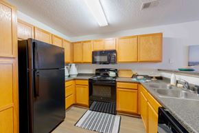 Winston Salem apartment for rent - A kitchen with wooden cabinets and a black refrigerator.