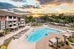 Charleston apartment for rent - A large swimming pool surrounded by lounge chairs and palm trees.