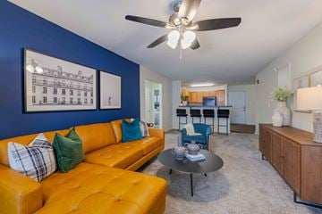 Fayetteville apartment for rent - A living room with a yellow couch and a ceiling fan.