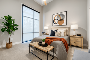 North Richland Hills apartment for rent - A bedroom with a bed, nightstand, and a plant.