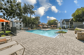 Arlington apartment for rent - A pool surrounded by a brick patio with a few chairs and umbrellas.