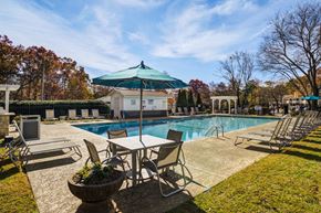 Taylors apartment for rent - A pool area with chairs and a table under a green umbrella.