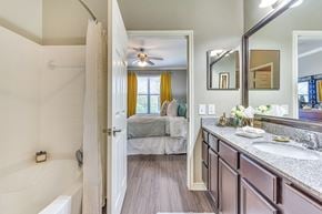 Mckinney apartment for rent - A bathroom with a white tub and a bedroom with a bed and a window.