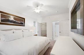 Dallas apartment for rent - a white bedroom with a large bed and a ceiling fan