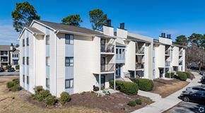 Wilmington apartment for rent - A row of white apartment buildings with balconies and a clear blue sky above.