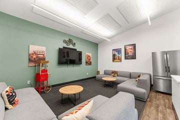 Raymore apartment for rent - A living room with a grey couch, a wooden table, and a television on the wall.