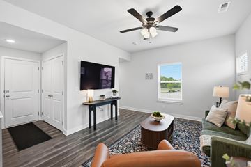 Kansas City apartment for rent - A living room with a ceiling fan and a television on the wall.