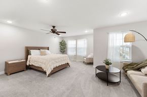 Bonner Springs apartment for rent - A bedroom with a large bed, a couch, and a ceiling fan.