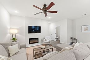 Bonner Springs apartment for rent - A living room with a grey couch, a fireplace, and a television mounted on the wall.