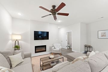 Bonner Springs apartment for rent - A living room with a grey couch, a fireplace, and a television mounted on the wall.