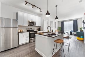 Kansas City apartment for rent - A modern kitchen with a stainless steel refrigerator and wooden bar stools.