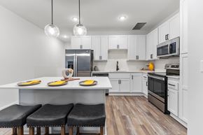 Raymore apartment for rent - Three-Bedroom Townhomes in Raymore, MO - Ascend - Bright White Kitchen With Large Island Seating, Globe Pendant Lights, And Stainless Steel Appliances.