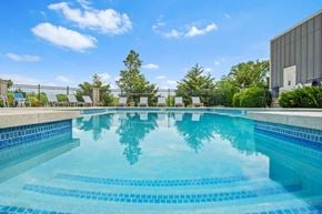 Lawrence apartment for rent - Lawrence, KS, Apartments for Rent - Fairway Flats & The Heights at Fairway Flats - Resort Style Pool With Blue Tile Steps, Lounge Seating, Black Metal Fence, Green Landscaping, And Open Sky.