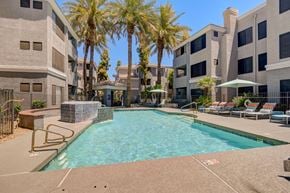 Phoenix apartment for rent - A swimming pool surrounded by palm trees and lounge chairs.