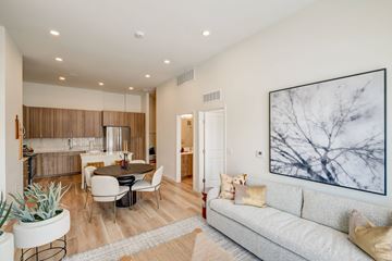 Aurora apartment for rent - A living room with a grey couch, a table with chairs, a potted plant, and a large painting on the wall.