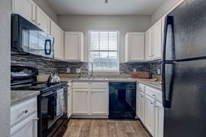 Dallas apartment for rent - A kitchen with black appliances and white cabinets.
