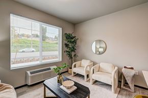 Tacoma apartment for rent - A living room with a large window, a couch, a chair, a coffee table, and a potted plant.