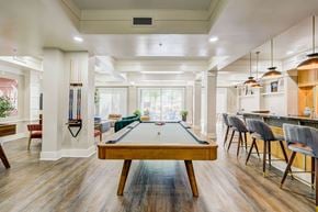 Peoria apartment for rent - A pool table is in the middle of a room with a billiard stick holder on the wall.