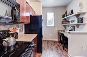 Fort Worth apartment for rent - A kitchen with a black refrigerator and a black stove top oven.