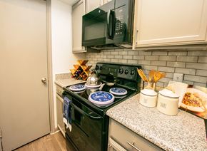 San Antonio apartment for rent - A kitchen with a black stove top and a black microwave above it.