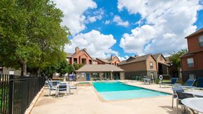 San Antonio apartment for rent - A swimming pool surrounded by a black fence and chairs.