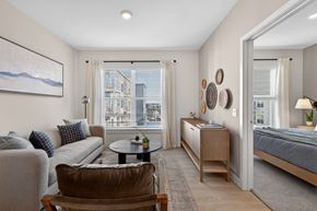 Waltham apartment for rent - A well-lit bedroom with a large bed and a view of the city through the window.
