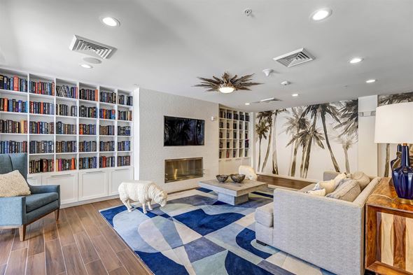 Miami apartment for rent - A white dog is standing on a rug in a living room with a bookshelf and a fireplace.