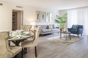 Tamarac apartment for rent - A dining room with a table set for two and a couch with a blue throw pillow.