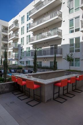 Glendale apartment for rent - A white building with balconies and a pool table with red chairs in front.