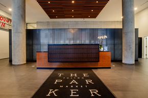Chicago apartment for rent - The lobby of The Park Ker, a modern and sleek space with a wooden ceiling and a black carpet.