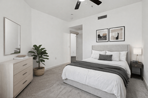 Plano apartment for rent - A bedroom with a large bed, a dresser, and a ceiling fan.