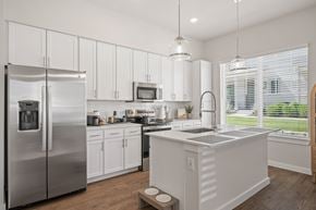 Mckinney apartment for rent - A modern kitchen with white cabinets and stainless steel appliances.