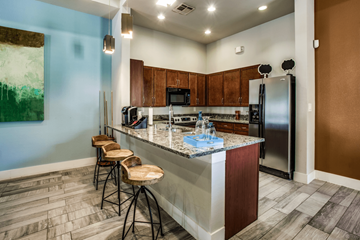 Grand Prairie apartment for rent - A kitchen with a blue wall and a counter with a refrigerator and microwave.
