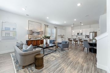Sherman apartment for rent - A spacious living room with a grey sofa, a coffee table, and a dining table set up.