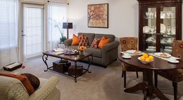 Fort Worth apartment for rent - A living room with a grey couch, a coffee table, and a dining table set for two.