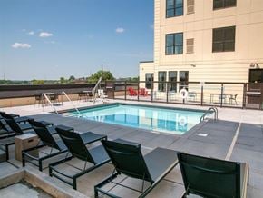 St Paul apartment for rent - A pool area with chairs and a building in the background.