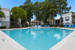 Tyler apartment for rent - A large swimming pool surrounded by trees and chairs.