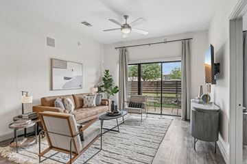 Plano apartment for rent - A living room with a couch, chair, and a table with a lamp on it.