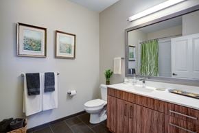 Medford apartment for rent - A bathroom with a toilet, sink, mirror, and two pictures on the wall.